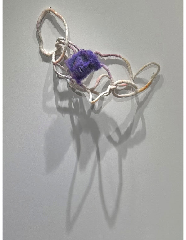 purple needle felted wool sculpture of a face affixed to a while woolen amorphous shape