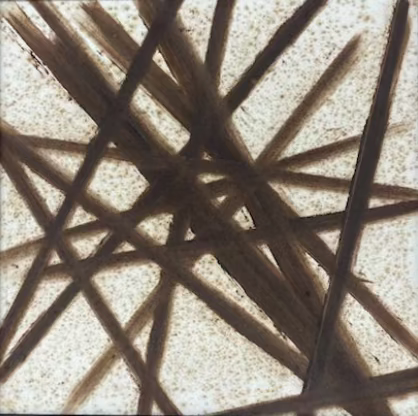 Framed abstract art with interwoven lines on a textured wall.