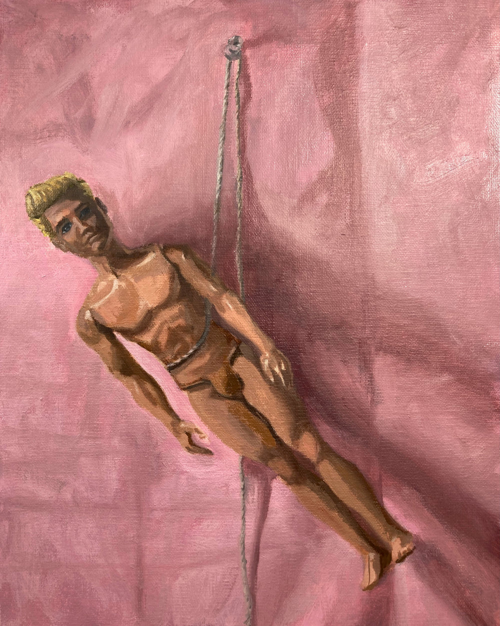 painting of a nude Ken doll hung on a wall by string