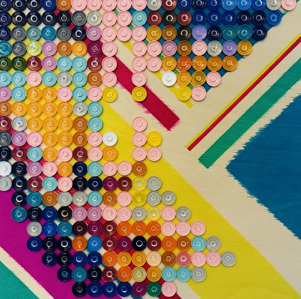 multi-colored medicine caps on a painted wood board; artwork appears abstract up close and forms into a portrait when viewed further away