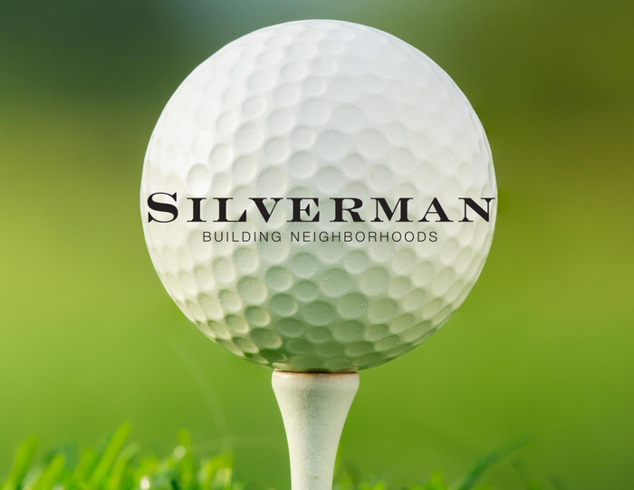 Siverman logo on large golf ball in front of green glass